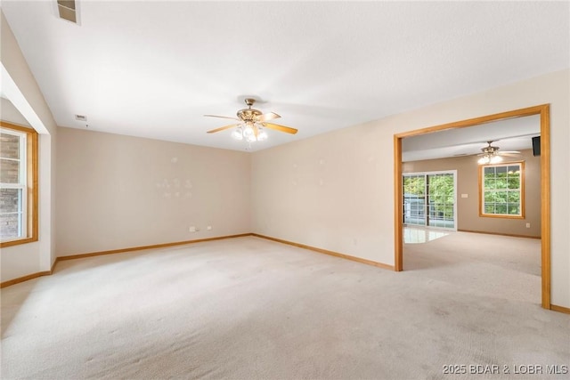 carpeted spare room with a ceiling fan and baseboards