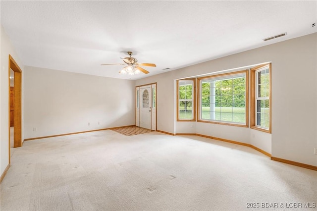 empty room featuring light colored carpet, baseboards, and ceiling fan