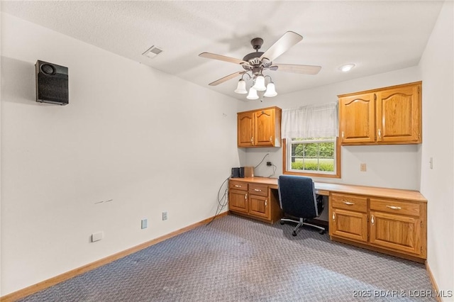 office with light colored carpet, built in study area, ceiling fan, and baseboards