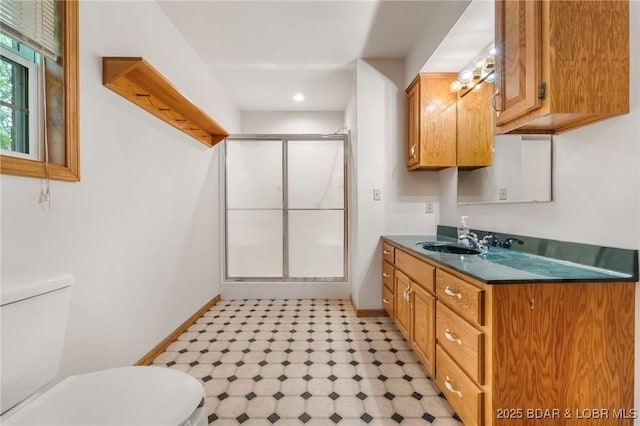 full bathroom with toilet, a shower stall, baseboards, and vanity