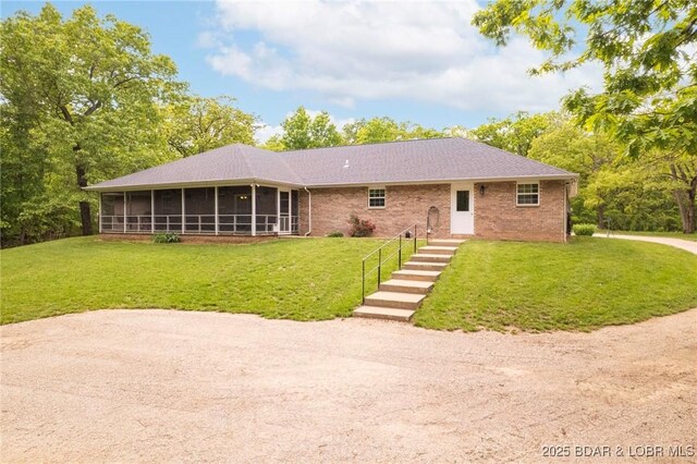 single story home with a sunroom, a front yard, and brick siding