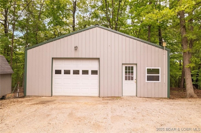 detached garage featuring view of scattered trees