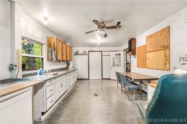 kitchen with dishwasher, ceiling fan, concrete flooring, brown cabinetry, and light countertops