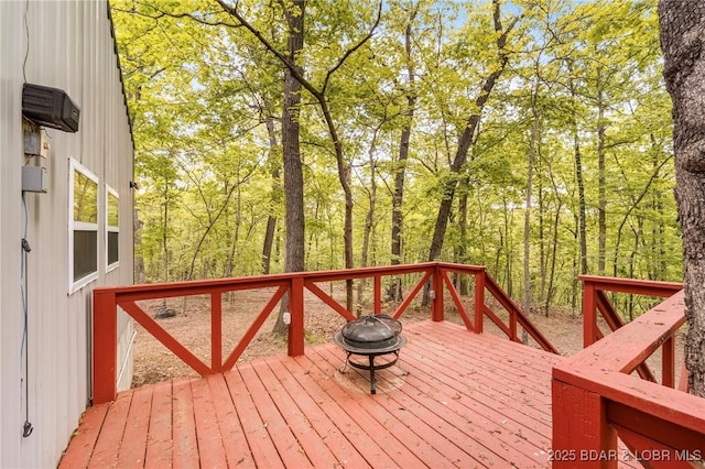 wooden terrace featuring an outdoor fire pit and a view of trees