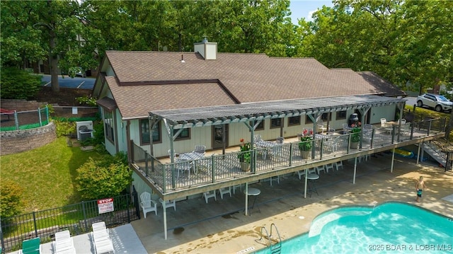 rear view of property with roof with shingles, fence, a chimney, and a community pool