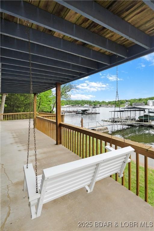 wooden terrace featuring a dock, a water view, and boat lift