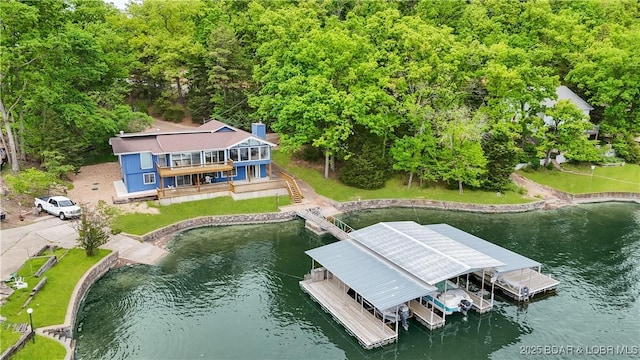 dock area featuring a view of trees, a lawn, stairway, and a deck with water view
