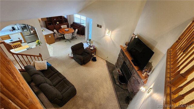 living room with carpet flooring, a fireplace, arched walkways, and stairs