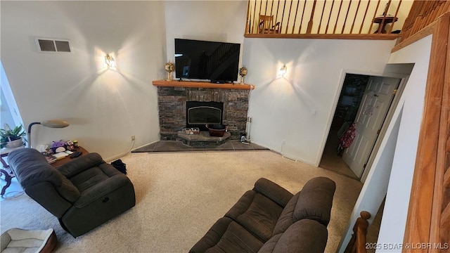 carpeted living room featuring a stone fireplace and baseboards