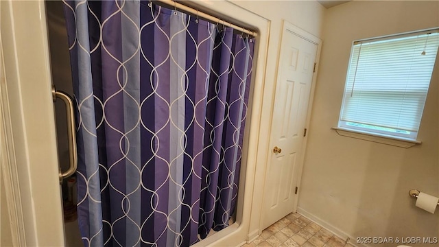 full bath with baseboards, a shower with shower curtain, and stone finish flooring