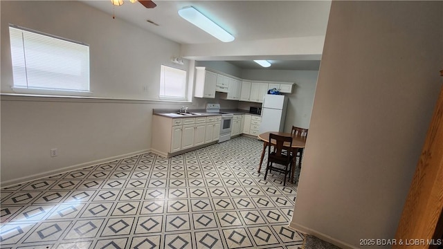 kitchen with white appliances, baseboards, white cabinetry, ceiling fan, and a sink