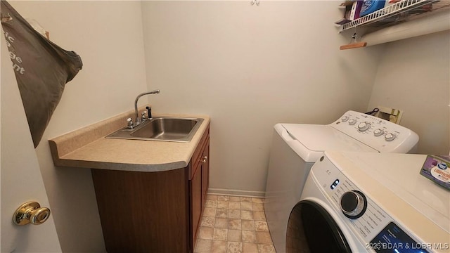 laundry area featuring a sink, washing machine and clothes dryer, light stone finish floors, and baseboards