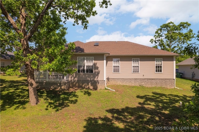 rear view of property featuring a yard and a shingled roof