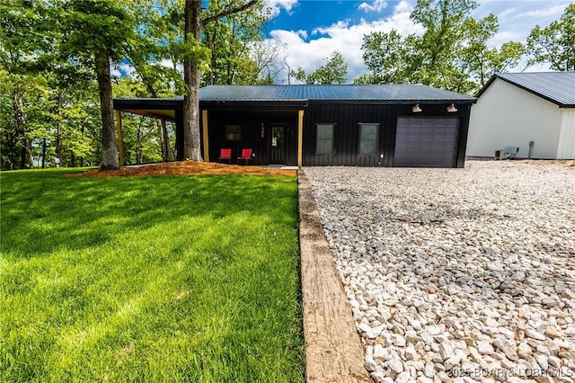 view of front of home with metal roof, a front yard, an attached garage, driveway, and board and batten siding