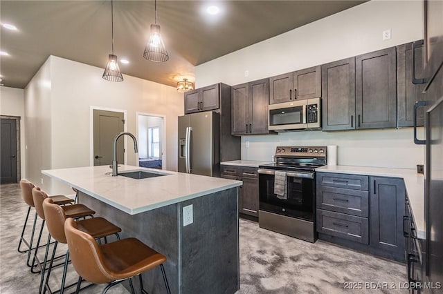 kitchen featuring appliances with stainless steel finishes, a sink, a breakfast bar area, a center island with sink, and pendant lighting