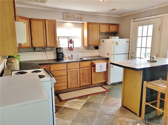 kitchen with white appliances, a sink, plenty of natural light, crown molding, and stone tile floors