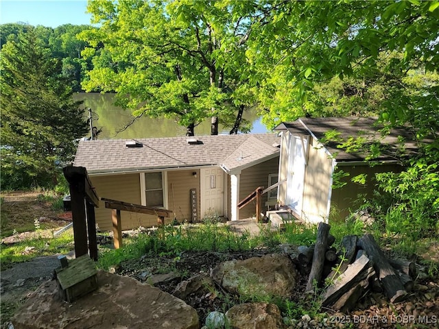 view of front of property with roof with shingles and a storage shed