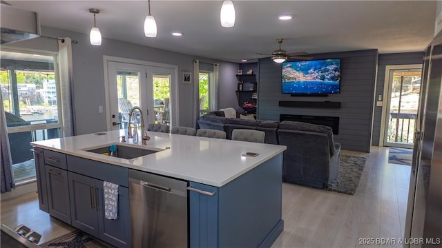 kitchen featuring a sink, stainless steel dishwasher, healthy amount of natural light, light wood-type flooring, and recessed lighting