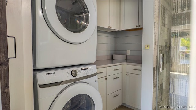 laundry area featuring stacked washer / drying machine and cabinet space