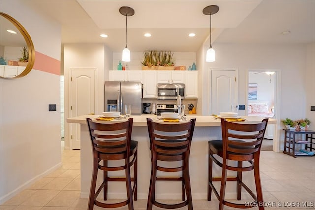 85 Monarch Cove Ln Unit 2C, Lake Ozark, MO 65049 - kitchen with appliances with stainless steel finishes, light countertops, light tile patterned flooring, white cabinetry, and hanging light fixtures