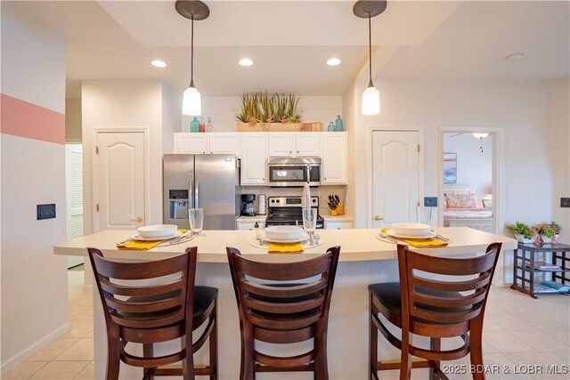 85 Monarch Cove Ln Unit 2C, Lake Ozark, MO 65049 - kitchen with stainless steel appliances, light countertops, light tile patterned floors, white cabinetry, and a breakfast bar