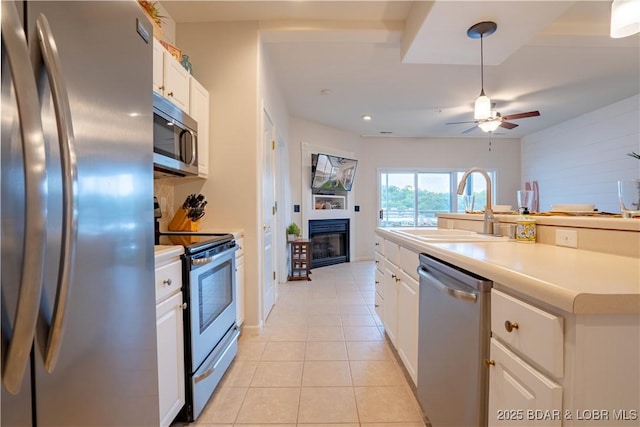 85 Monarch Cove Ln Unit 2C, Lake Ozark, MO 65049 - kitchen featuring stainless steel appliances, a sink, a glass covered fireplace, ceiling fan, and light tile patterned floors