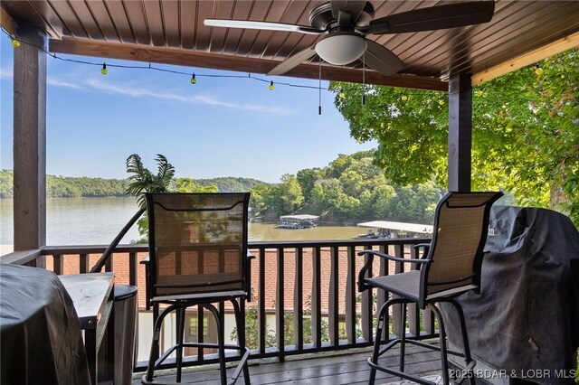 deck with a ceiling fan and a water view