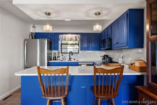 kitchen with blue cabinetry, freestanding refrigerator, black microwave, and a sink