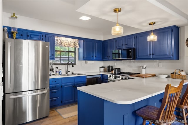 kitchen with stainless steel appliances, a sink, blue cabinets, and a peninsula