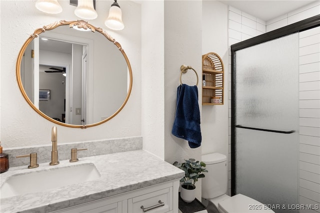 bathroom featuring toilet, vanity, a ceiling fan, and an enclosed shower