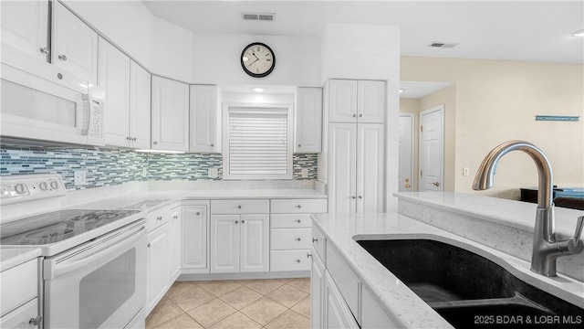 kitchen with white appliances, a sink, white cabinetry, and decorative backsplash