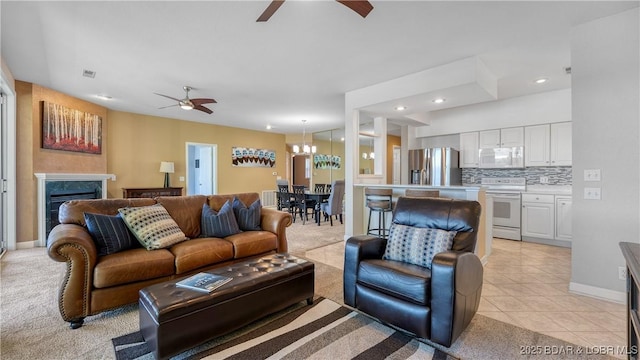 living area with ceiling fan, a chandelier, a fireplace, recessed lighting, and light tile patterned floors