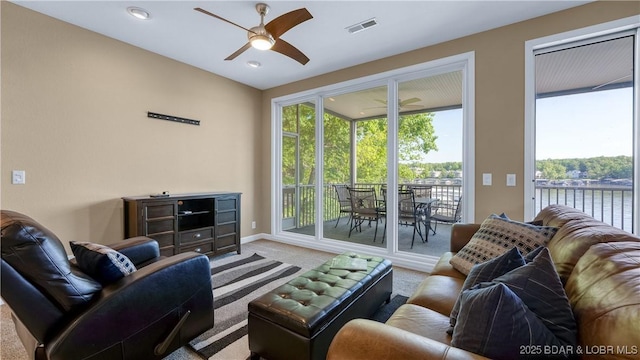 carpeted living area featuring a ceiling fan, plenty of natural light, baseboards, a water view, and recessed lighting