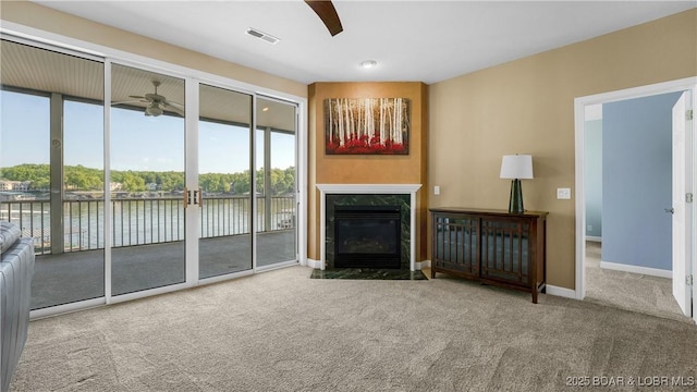 living area with a ceiling fan, carpet, a water view, a premium fireplace, and baseboards