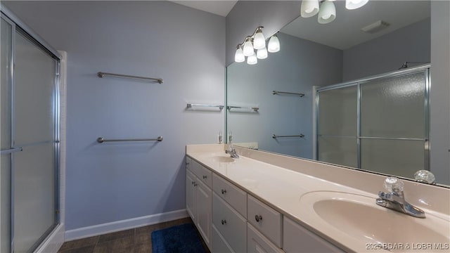 full bathroom with a shower with shower door, double vanity, baseboards, and wood finished floors