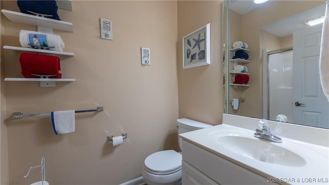 bathroom with toilet, vanity, and a shower with shower door