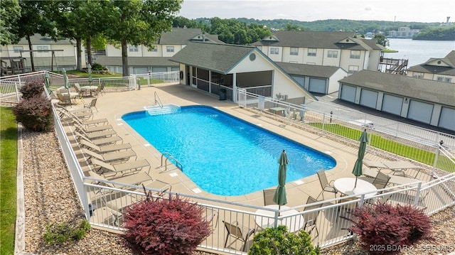 community pool featuring a patio area, a sunroom, fence, and a residential view