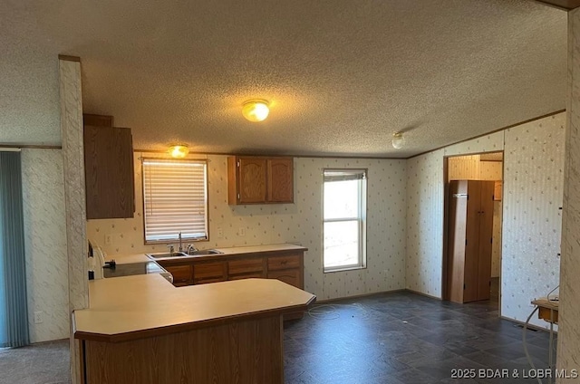 20877 Twin Hills Dr, Warsaw, MO 65355 - kitchen with a textured ceiling, wallpapered walls, a sink, lofted ceiling, and brown cabinetry
