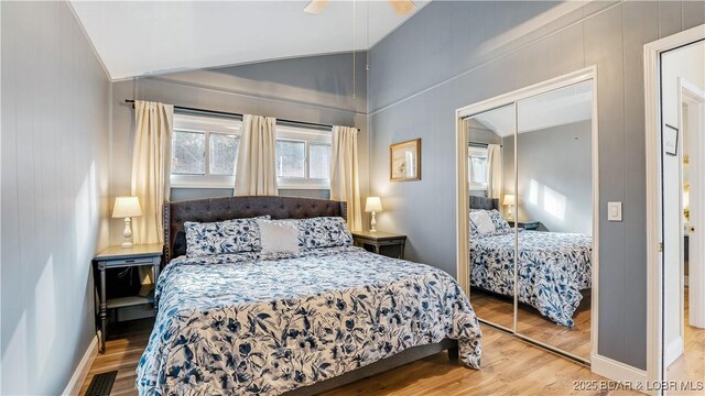 bedroom with lofted ceiling, wood finished floors, a closet, a ceiling fan, and baseboards
