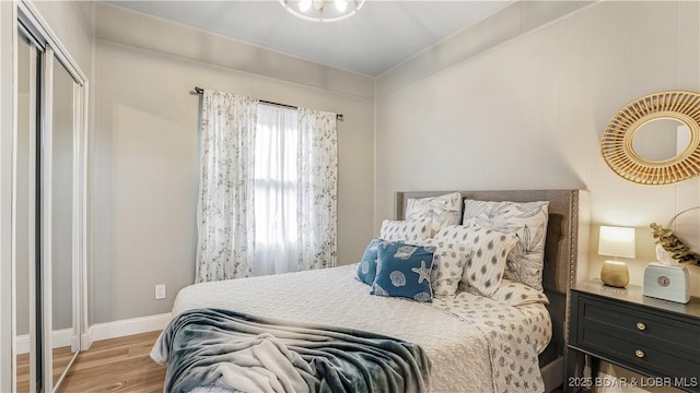 bedroom with wood finished floors, baseboards, and a closet
