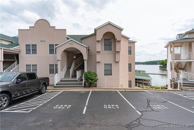 214 Emerald Bay Dr Unit 1D, Lake Ozark, MO 65049 - view of property featuring stairway, uncovered parking, and a water view