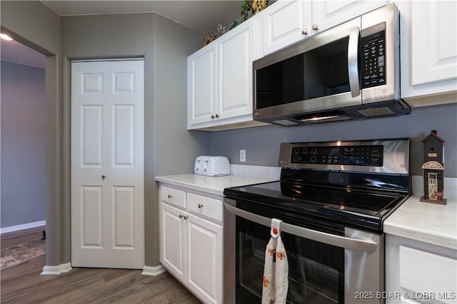 214 Emerald Bay Dr Unit 1D, Lake Ozark, MO 65049 - kitchen featuring stainless steel appliances, wood finished floors, light countertops, and white cabinets