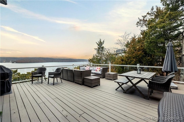 deck with outdoor lounge area, a water view, and a grill