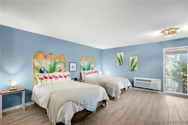 bedroom featuring a wall mounted air conditioner, wood finished floors, and baseboards