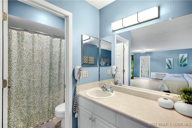bathroom with ensuite bathroom, an AC wall unit, vanity, and toilet
