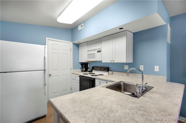 kitchen with white appliances, a sink, wood finished floors, white cabinets, and light countertops