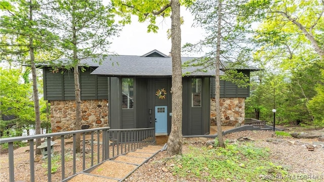 view of front of house featuring stone siding and roof with shingles