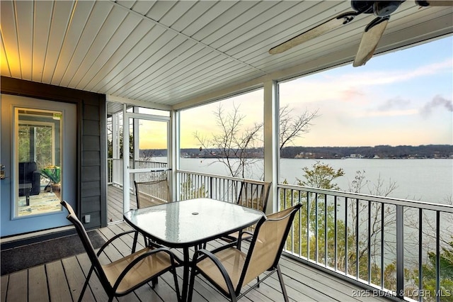 sunroom / solarium with a water view, outdoor dining space, and a ceiling fan