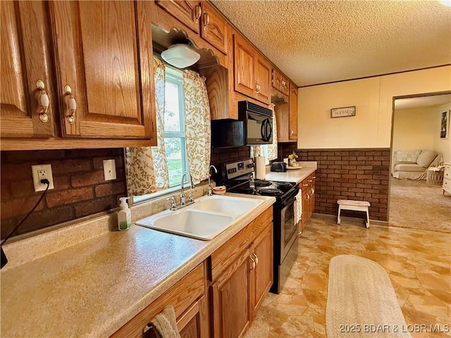kitchen with stainless steel electric stove, a sink, black microwave, brown cabinetry, and a textured ceiling