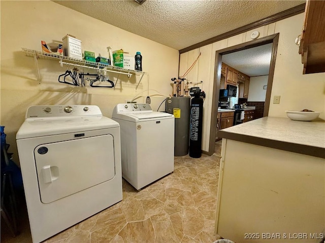 clothes washing area with water heater, washer and clothes dryer, a textured ceiling, and cabinet space